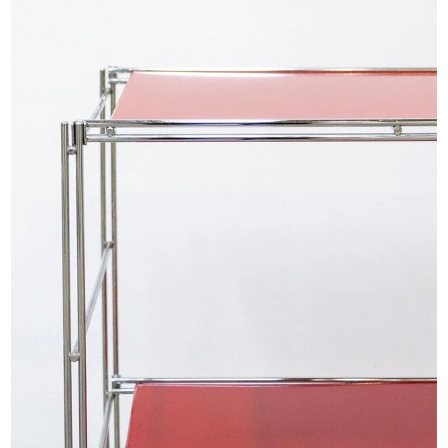 80s metal bookcase shelving unit Chromed steel structure, three red metal shelves that snap together The shelving unit has...