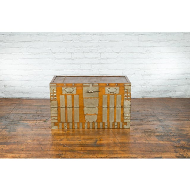 An antique Korean storage chest from the early 20th century, with silver plated brass hardware and drop down panel....