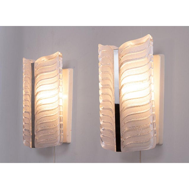 Elegant set of two large wall sconces made of heavy, thick murano glass with a chrome-plated center piece on a white metal...