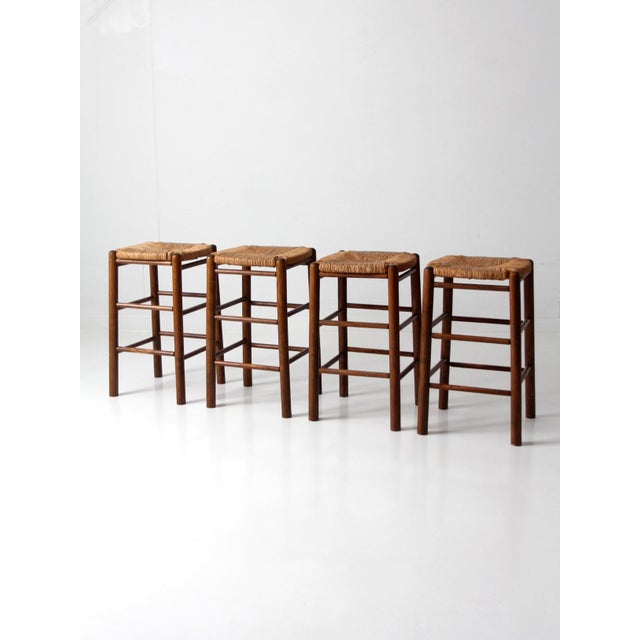 A set of four mid-20th century rush seat stools with a Danish modern sensibility. Turned wood frames are paired with...