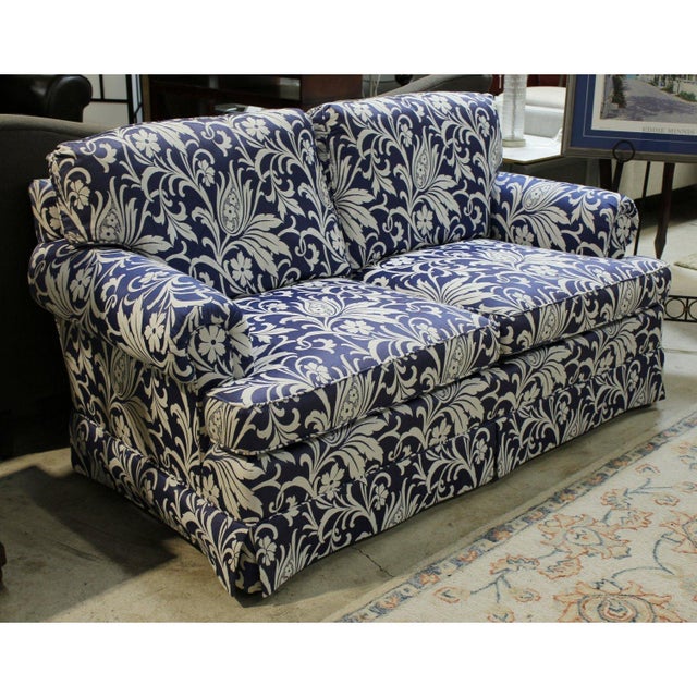 This loveseat features a bold botanical pattern with scrolling leaves and florals set against a deep blue background. Its...