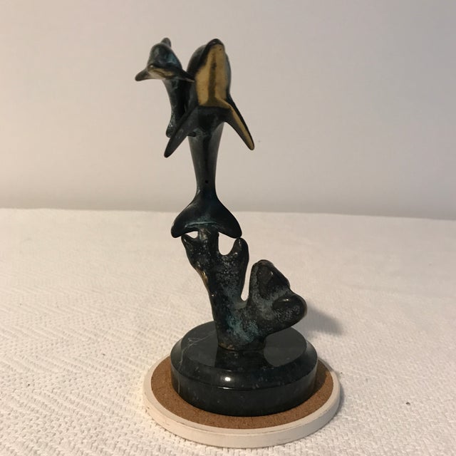 This beautiful brass sculpture of a mother dolphin and her baby captures the inherent nature of the mother and child bond....