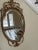 Exquisite gilt hand crafted mirror by Friedman Brothers. The mirror is oval with a beveled edge. This is an Adams styled...