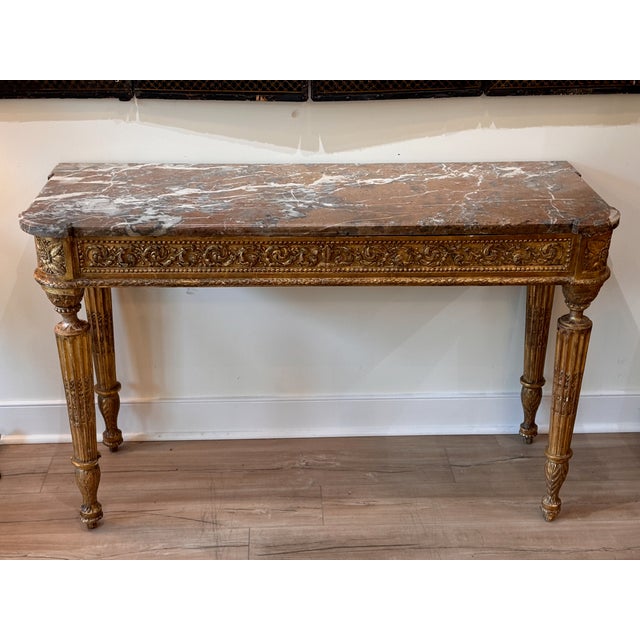 An elegant and solidly built carved giltwood French console with a variegated rouge marble top. The deep apron is carved...