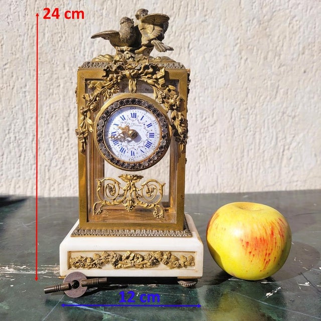 Small bronze and white marble clock in the Louis XVI style: richly ornamented with finely chased bronze garlands of...