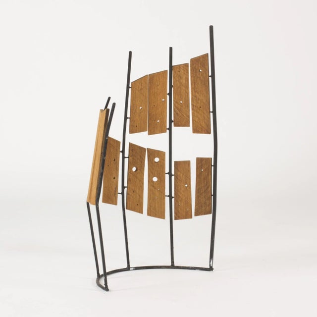 Beautiful sculpture by Fred Leyman, made with wood arranged on a black lacquered metal frame that is arched in the base....