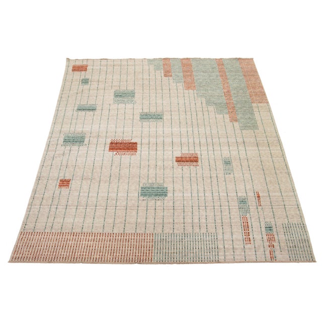 This hand-loomed modern wool rug is designed to captivate. Its elegant light beige background is a perfect canvas for the...