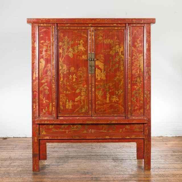 A Chinese Qing Dynasty period large armoire from the 19th century with red lacquer, gilt décor, two doors and front apron....
