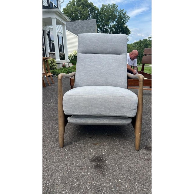 Stylish and comfortable Mid-Century Modern style reclining armchair featuring smooth sculptured wooden arms and clean...