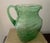 Mid Century Modern green glass pitcher is blown glass with an applied handle. It has a textured wavy surface and is...