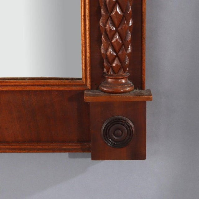 An antique Sheraton-style wall mirror, crafted from mahogany around 1830. This Federal period looking glass features a...