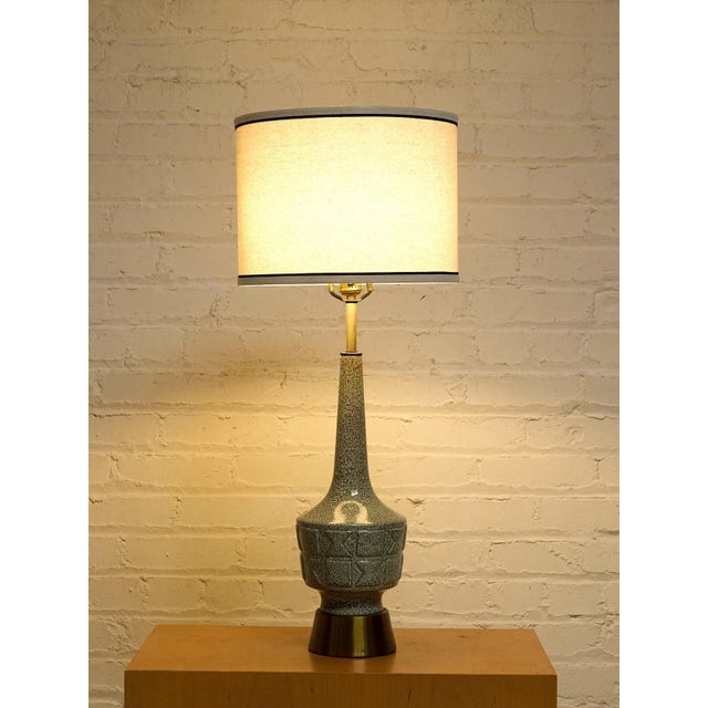 A striking vintage Mid-Century Modern table lamp featuring an elongated sculptural ceramic body covered in an intricate...