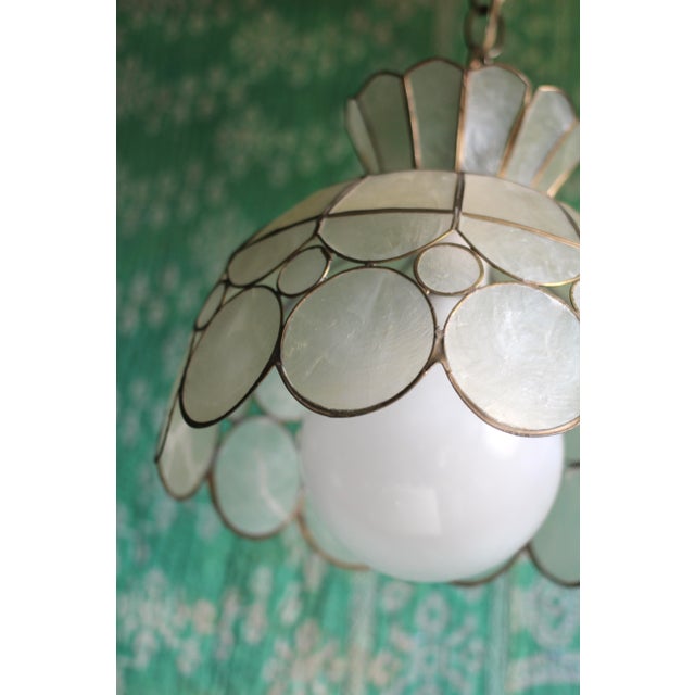 A wonderful pendant light fixture made of capiz shell panels and circles and brass. Holds a standard light bulbs and hangs...
