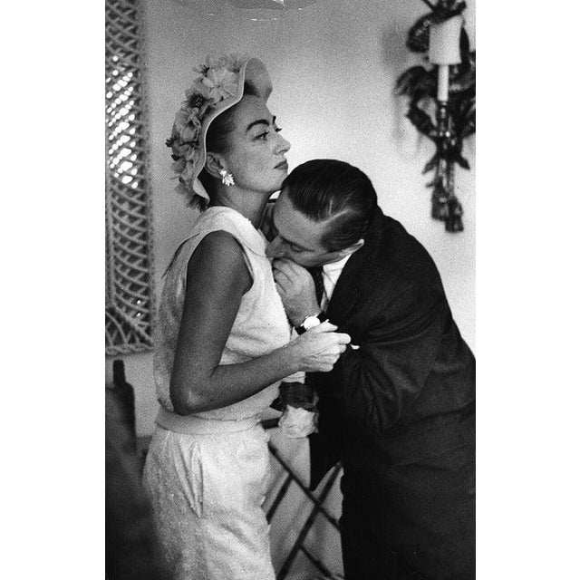 Joan Crawford American actress Joan Crawford (1906 - 1977) asks her assistant to bite off a loose thread from her dress at...