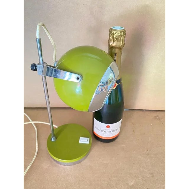 This table lamp is made of metal, and was made in Italy in the 1960s. It is in a mustard green color. Its eye-shaped...
