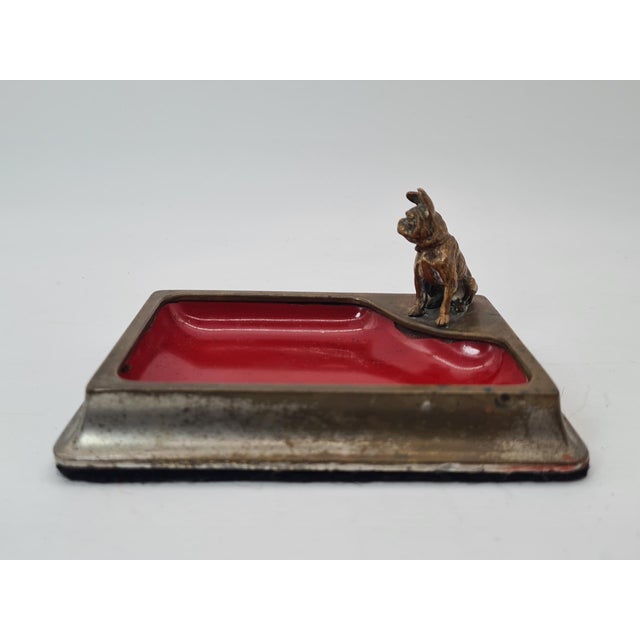 A unique, decorative vide-poche tray made of metal, featuring a striking, hand-sculpted bulldog made of bronze. The piece...