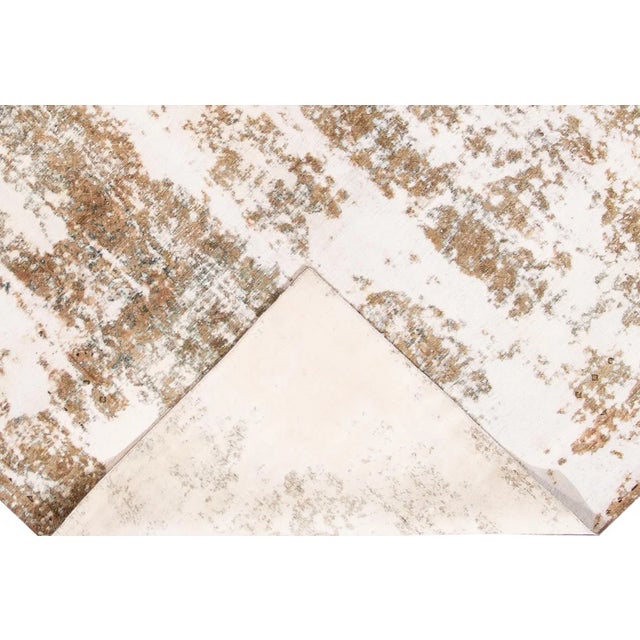 Beautiful hand-knotted vintage wool rug with a tan field. This distressed rug has white accents featuring a shabby chic...