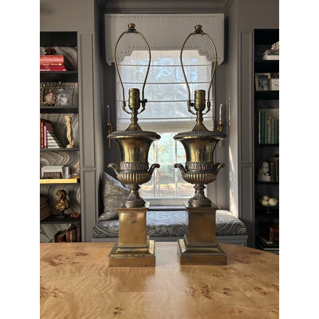 A pair of classical style brass urn and pedestal lamps in a polished brass finish with some patina as shown. Very...