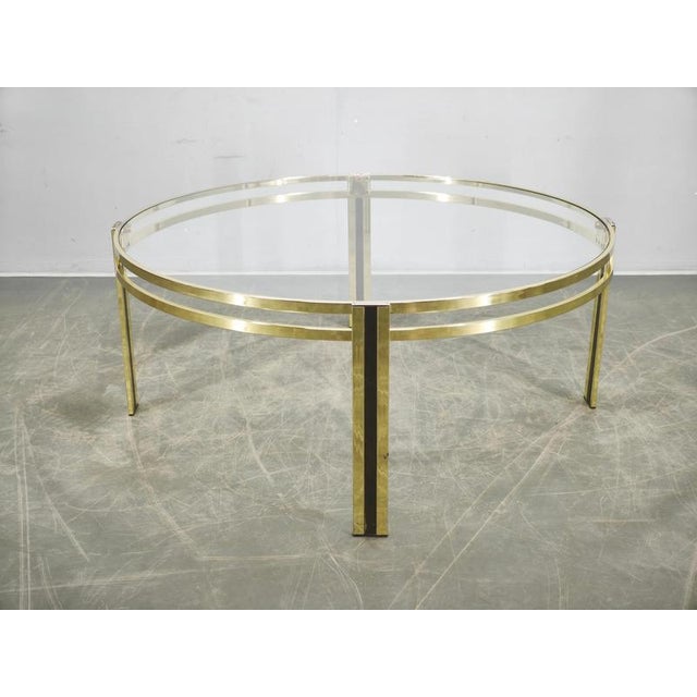 A sophisticated Italian coffee table from the 1970s, defined by its circular form and elegant brass-finished metal...