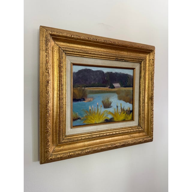 Serene marsh landscape painting featuring soft blue water, golden cattails and a distant barn. Painted in an...