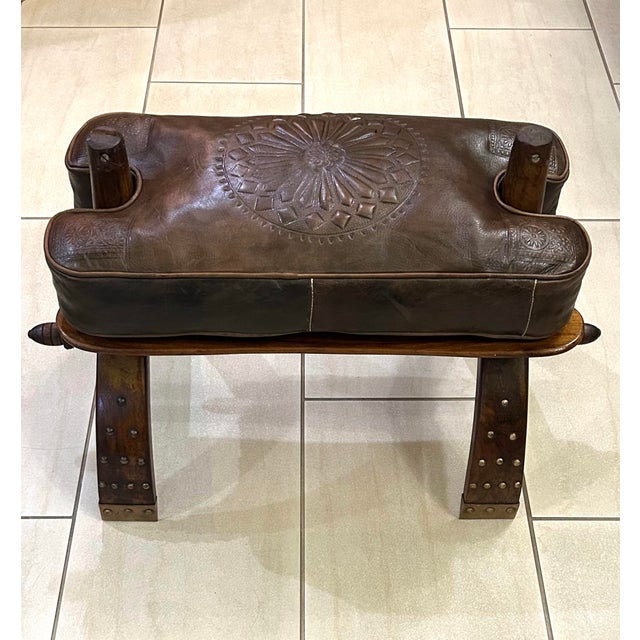 This is a dark-chocolate colored, hand-tooled, embossed, leather cushion on top of a richly stained, Egyptian camel...