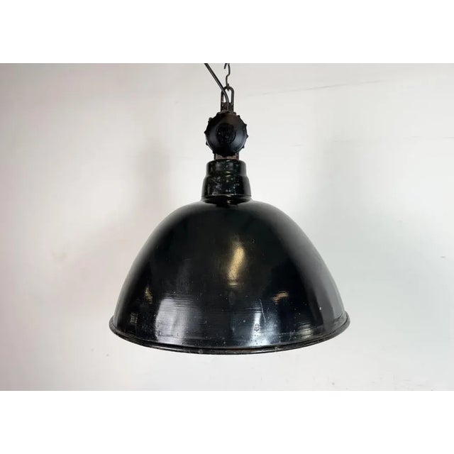 Industrial enamel factory light made by lbd veb leuchtenbau dresden in east germany during the 1950s.it features black...