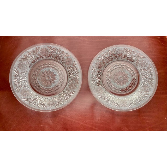 A pair of vintage scrollwork clear glass small plates in the Sandwich pattern that consists of a textured background of...