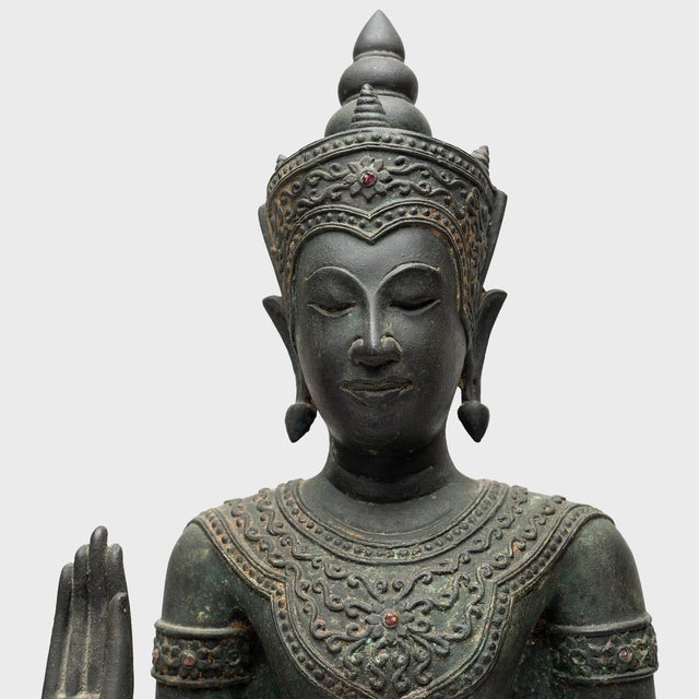 This standing Buddha figure from Thailand wears a serene expression of stillness and calm. Cast of bronze alloy in the...