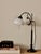 An elegant adjustable French table lamp in patinated bronze or bronzed brass, circa 1930s. The lamp features a slender...
