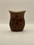 A hand carved wooden vessel decorated with a stylized flowering tree on a textured background with a zig zag border. This...