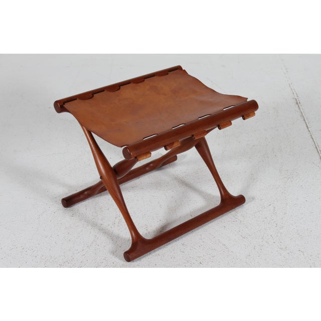 "Guldhøj" stool PH 41 with folding frame made of solid teak with seat of original strong cognac color leather. Made in the...