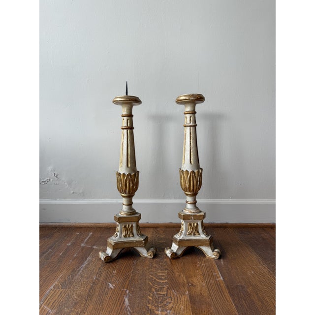 This pair of antique Baroque candlesticks is crafted from wood and adorned with gilded details, showcasing ornate period...