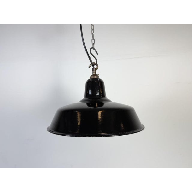 Industrial black enamel pendant light made in United Kingdom during the 1960s. White enamel inside the shade. Brass top....