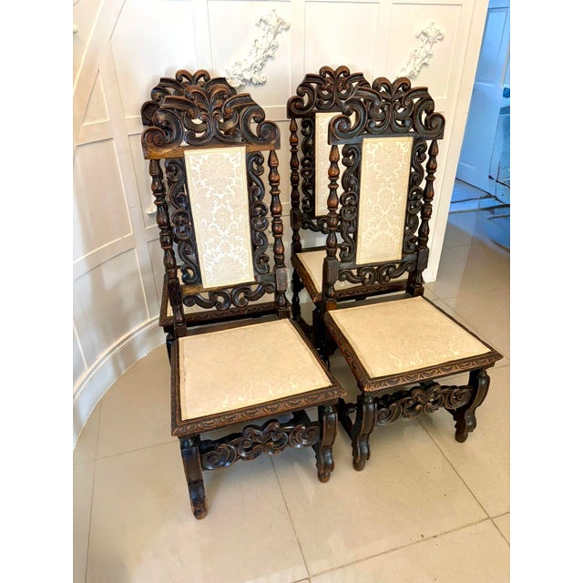 A striking set of four antique Victorian carved oak dining chairs each displaying superb depth of carving and strong...