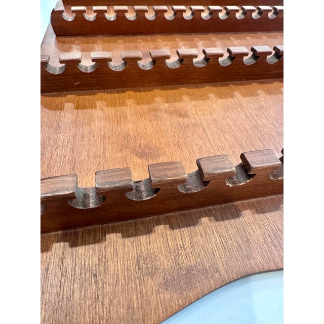 A warm, sculptural wooden rack designed to give a collection of souvenir spoons a place to be seen. Four horizontal rows...