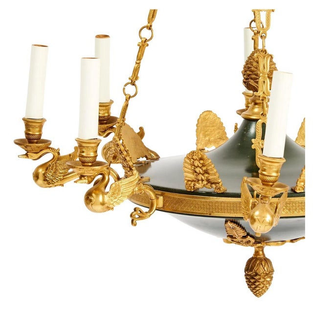 An empire style eight light chandelier featuring a dark green tole bowl accented with richly detailed gilt bronze mounts....