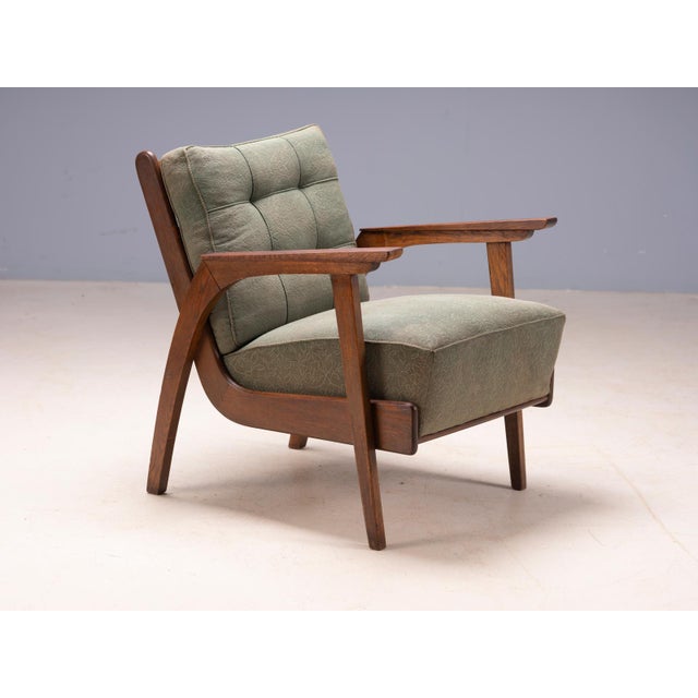 A distinctive pair of vintage mid-century lounge armchairs featuring sculpted wooden frames, curved wooden armrests,...
