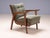 A distinctive pair of vintage mid-century lounge armchairs featuring sculpted wooden frames, curved wooden armrests,...