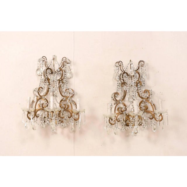 A pair of Italian mid-20th century crystal three-light wall sconces. This pair of Italian crystal sconces from the...