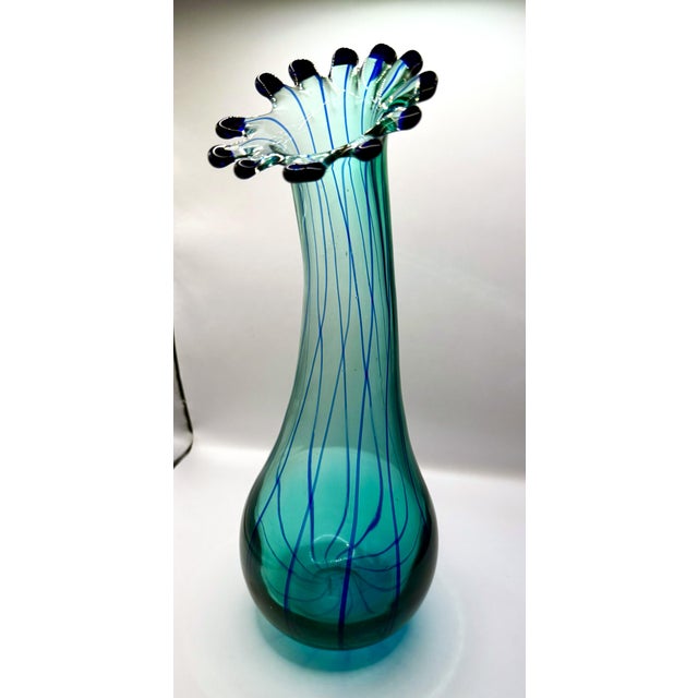 A striking hand‑blown studio art glass vase, signed Eastern, featuring a sculptural ruffled rim with applied cobalt tips...