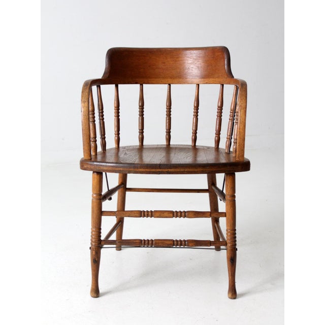 This antique Captain's chair displays the classic lines of early American design, including a curved backrest, spindle...