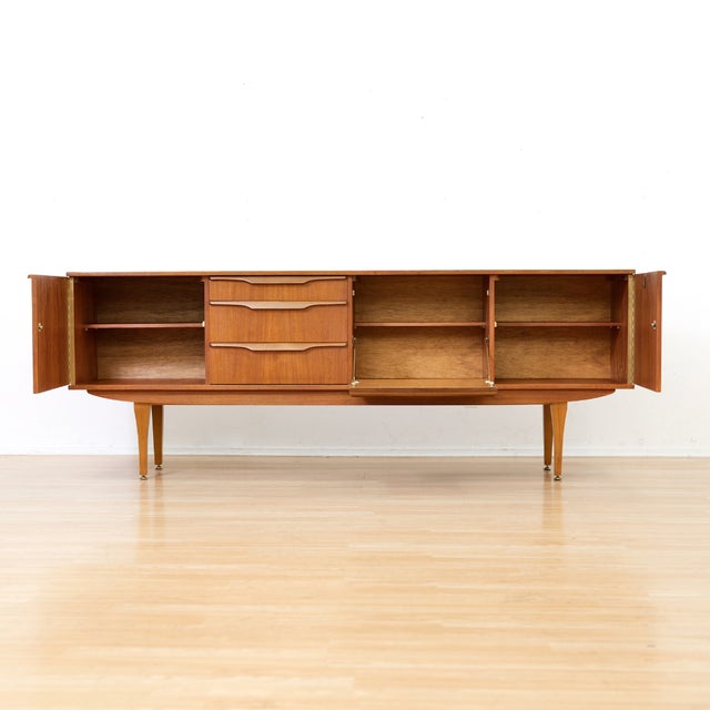 Designed and manufactured by Stonehill Furniture in England in 1960, this elegant mid-century sideboard embodies the...