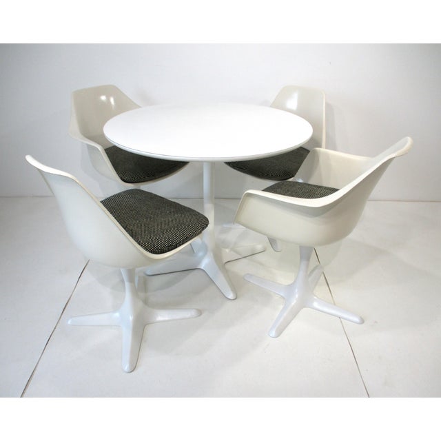 A five-piece Mid Century tulip dining set including a 42" table, two swiveling armchairs and two non-swiveling side chairs...