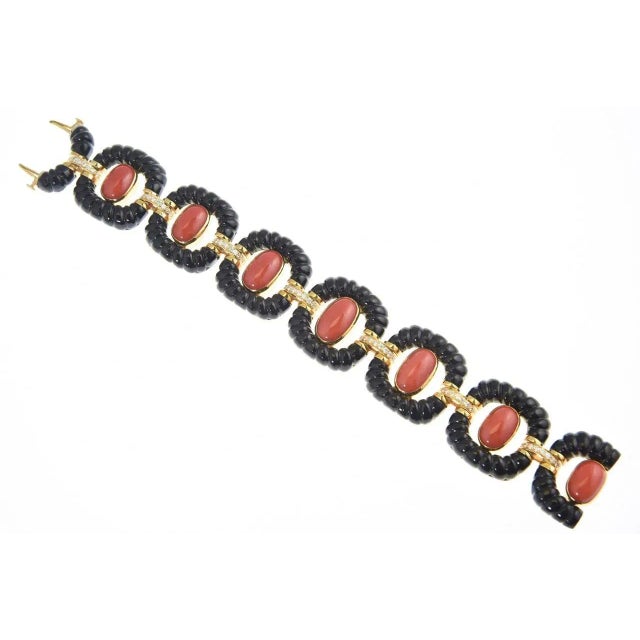 Incredible bracelet with links made of carved onyx frames with oval coral cabochons centers mounted in 14k yellow gold...