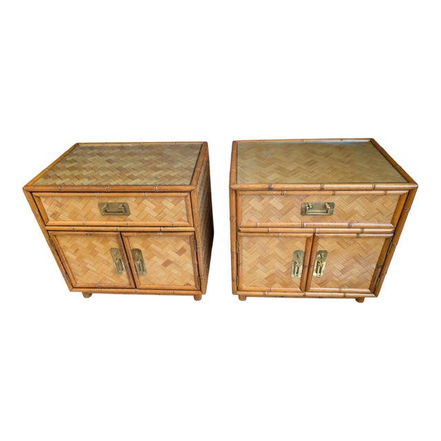 A striking vintage pair of nightstands featuring faux-bamboo framing, woven rattan fronts in a herringbone/parquet...