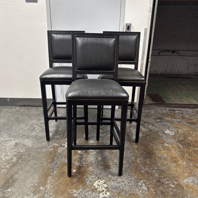 Design Plus Gallery presents a Set of Three Black Leather Barstools from Buying & Design. The black wood frames have...