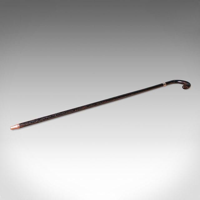This is a vintage walking cane. An English, ebonised mahogany and brass stick with hallmarked silver collar, dated to...