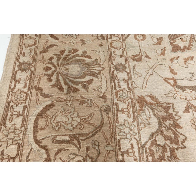 A hand-knotted wool antique Persian Tabriz rug dating back to 1930. The main field features a grid of enlarged palmettes,...