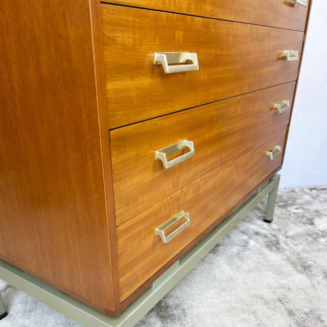 Afrormosia-veneered carcase construction on a painted metal stand base. Four full-width graduated drawers with dovetail...