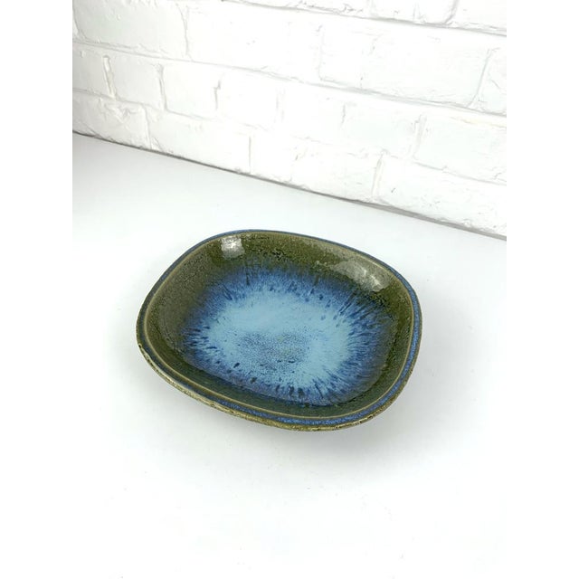 Large ceramic vide-poche or low bowl in olive green tones with an impressive blue flame in the center. The blue effects...